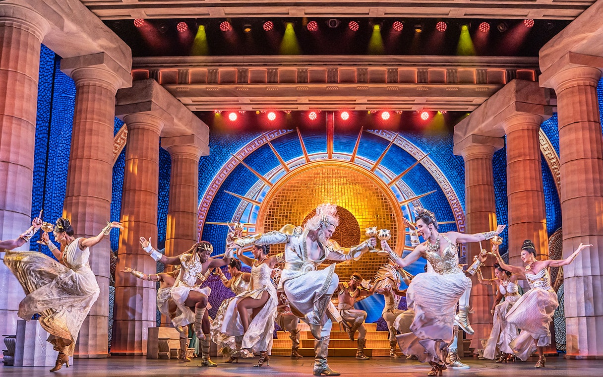 Performers dancing in a vibrant scene from Disney's Hercules stage show.