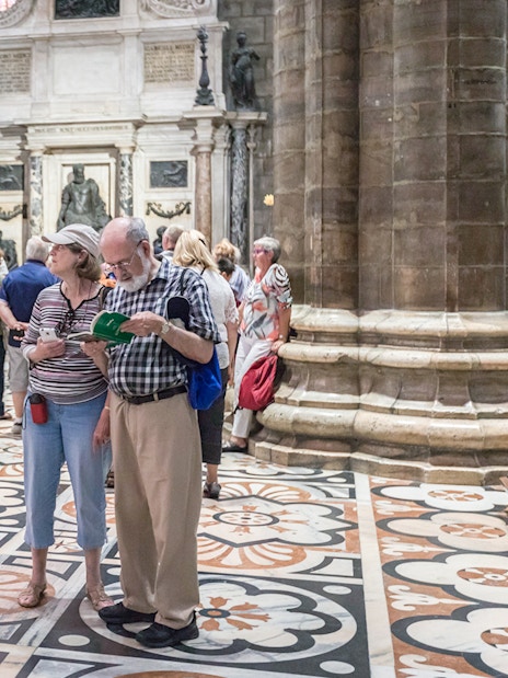 Tourists inside Milan Duomo Cathedral near Church of San Gottardo access.