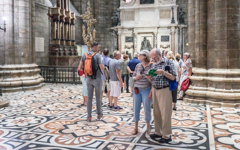Tourists inside Milan Duomo Cathedral near Church of San Gottardo access.
