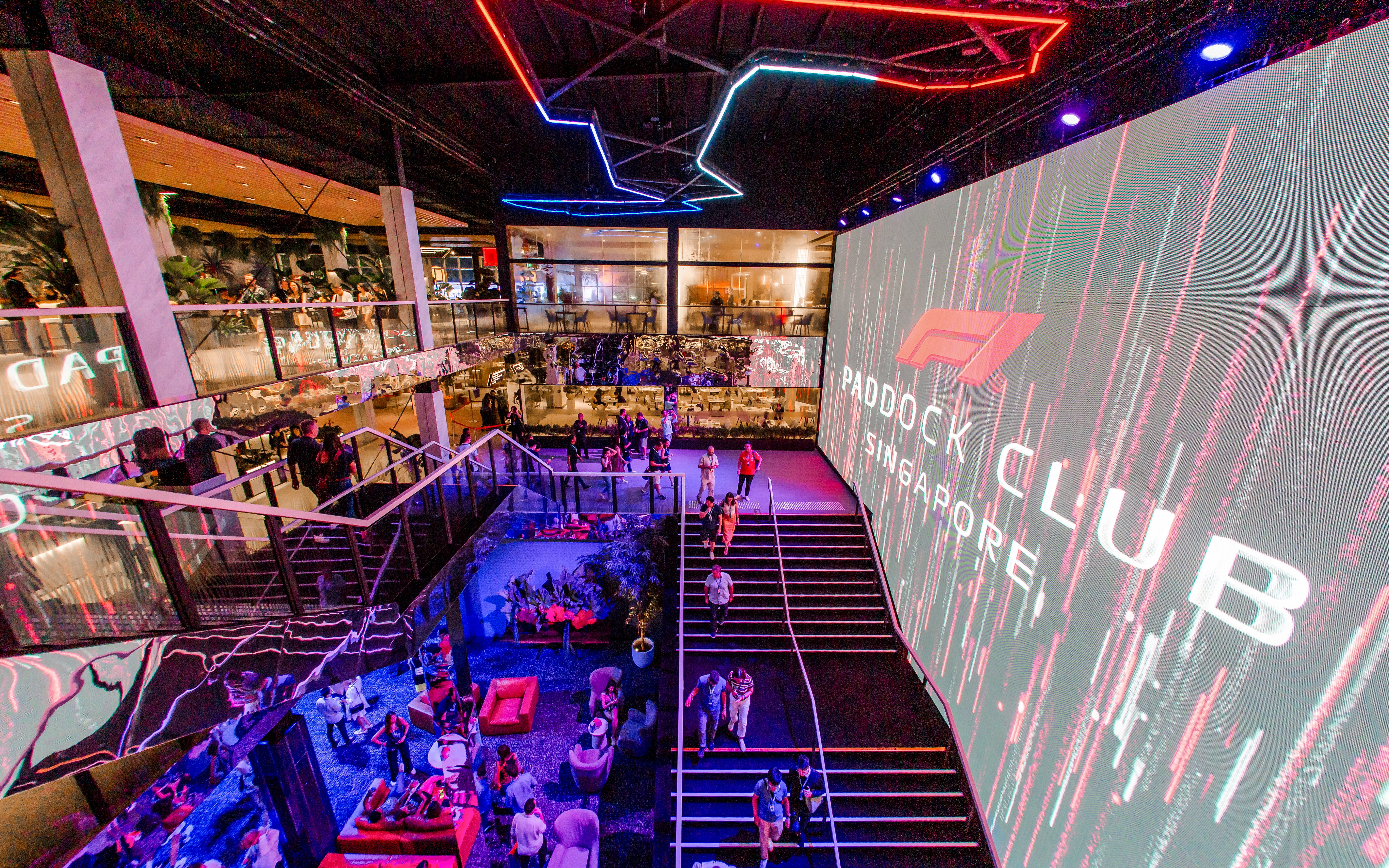 Paddock Club Singapore interior with guests and large digital display.