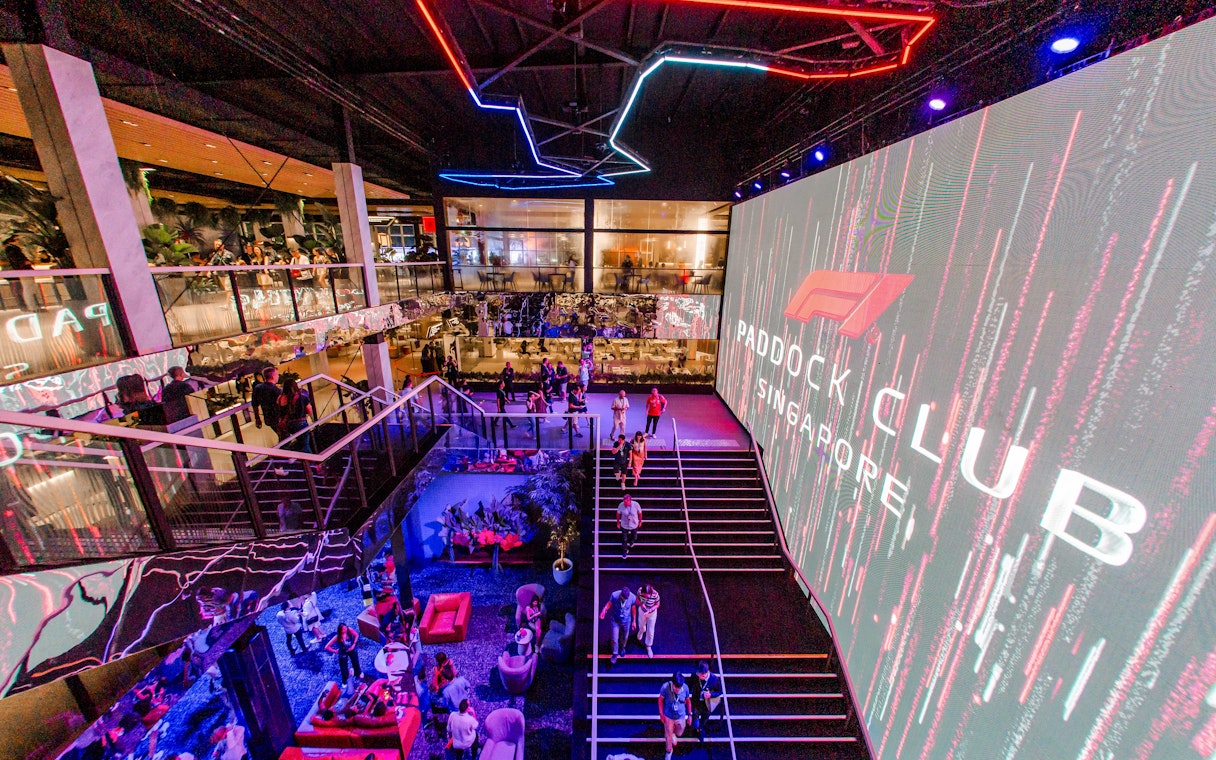 Paddock Club Singapore interior with guests and large digital display.