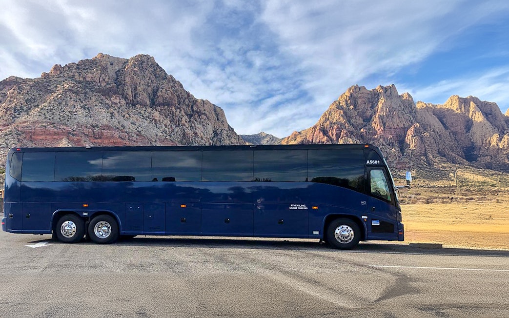 Tour bus parked with scenic mountain backdrop.