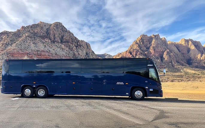 Tour bus parked with scenic mountain backdrop.
