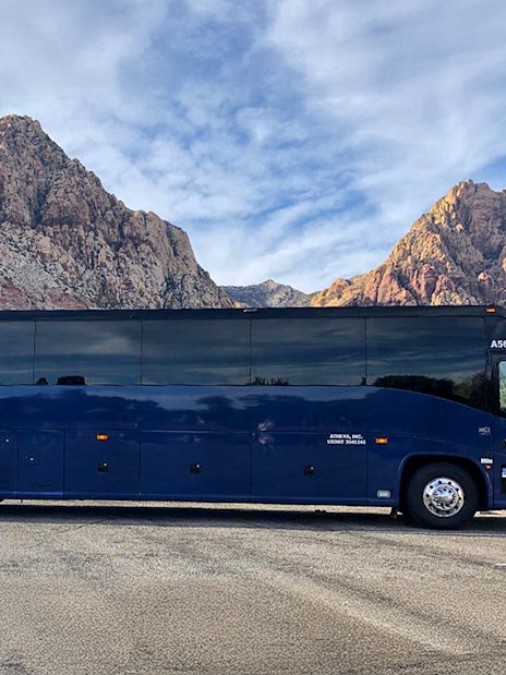 Tour bus parked with scenic mountain backdrop.