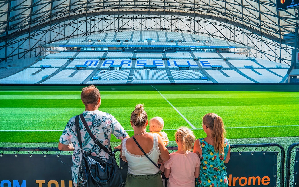 Family viewing the field at Marseille's OM Stadium during a tour.