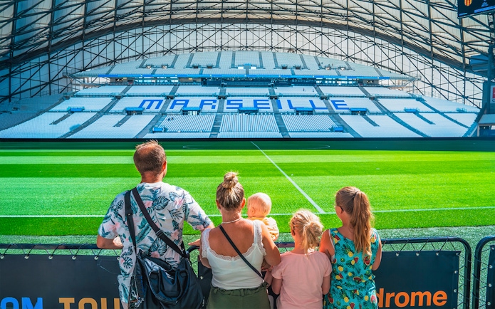 Family viewing the field at Marseille's OM Stadium during a tour.