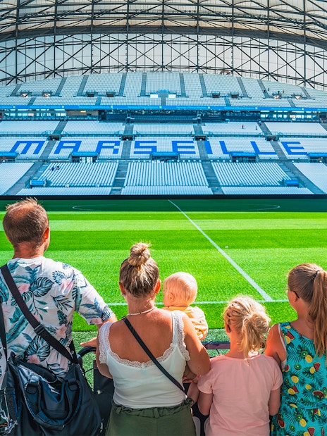 Family viewing the field at Marseille's OM Stadium during a tour.