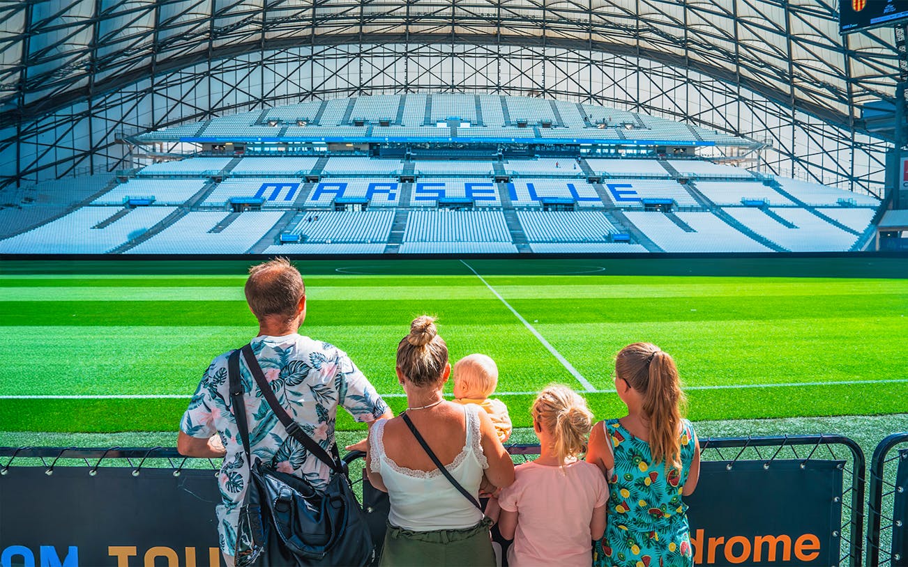 Family viewing the field at Marseille's OM Stadium during a tour.
