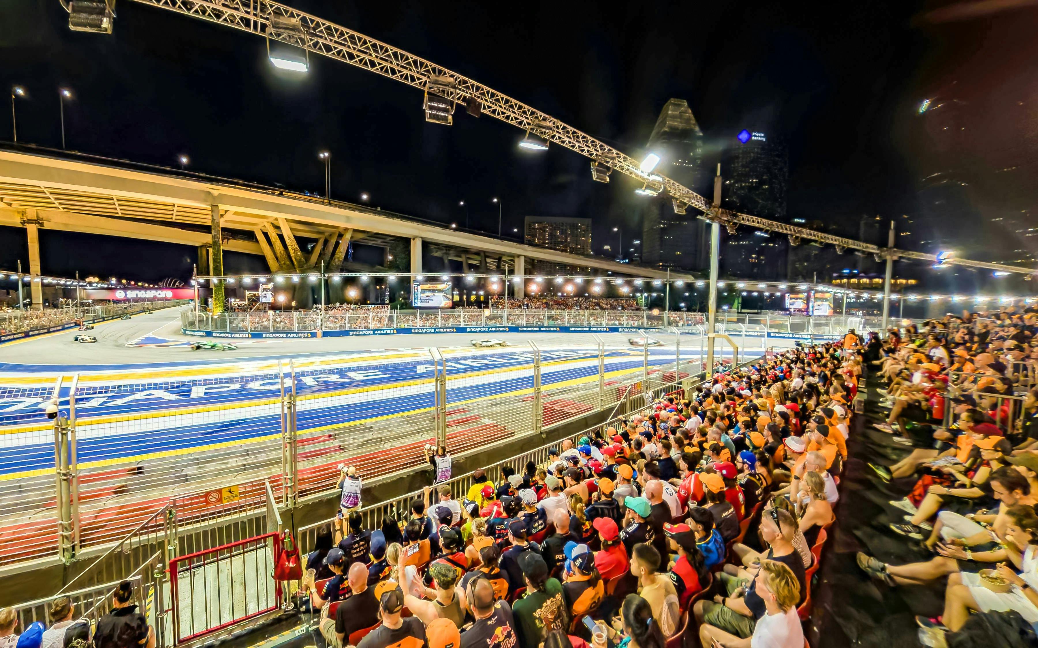 Spectators watching cars race from turn 2 Grandstand at Formula 1 Singapore Grand Prix.