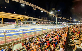 Spectators watching cars race from turn 2 Grandstand at Formula 1 Singapore Grand Prix.