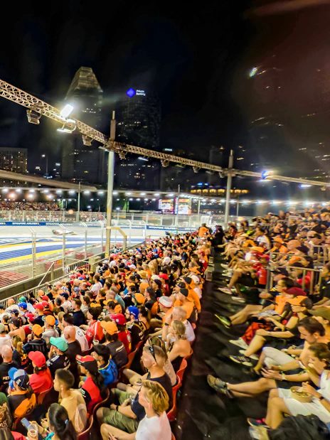 Spectators watching cars race from turn 2 Grandstand at Formula 1 Singapore Grand Prix.