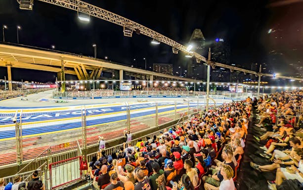 Spectators watching cars race from turn 2 Grandstand at Formula 1 Singapore Grand Prix.
