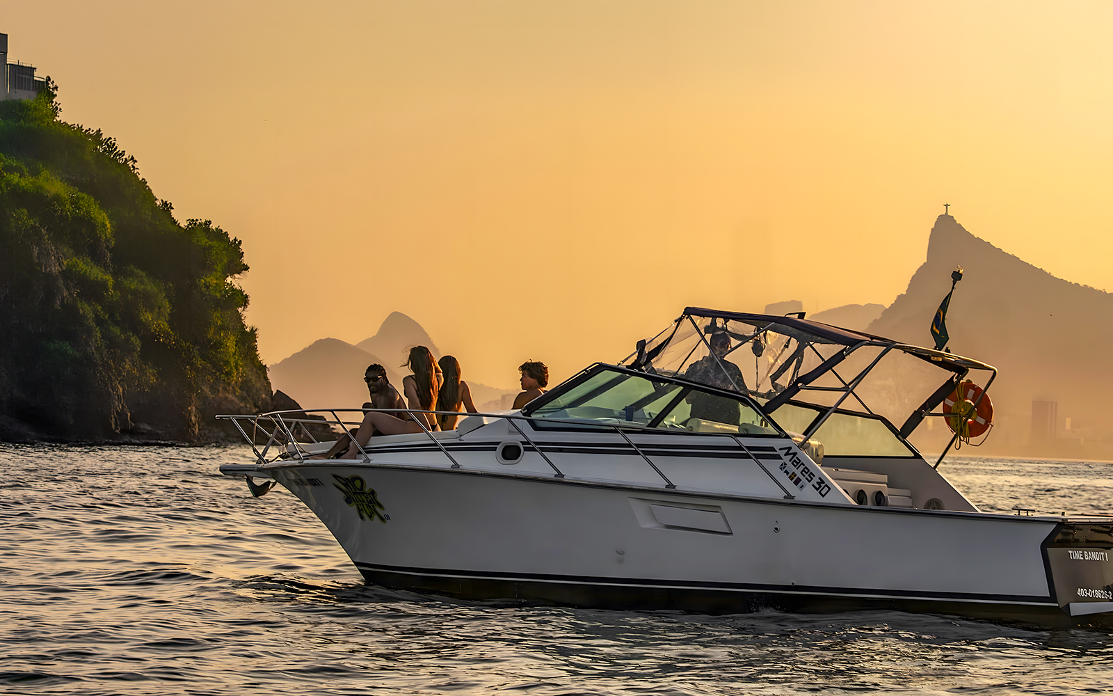 Tourists on a boat during Rio de Janeiro sunset cruise with Sugarloaf Mountain in view.
