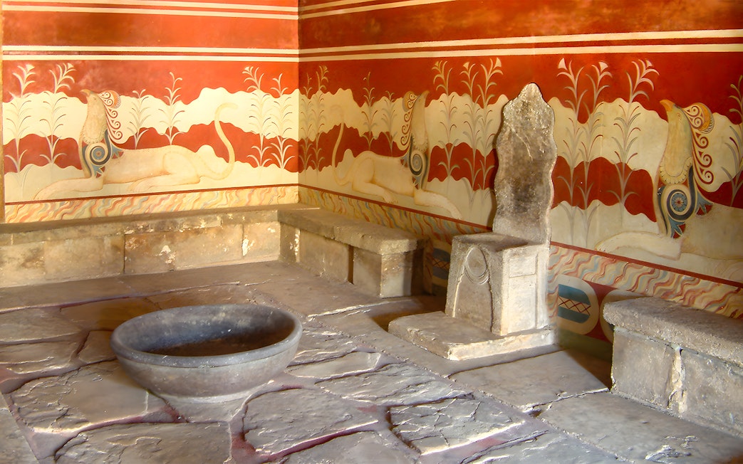 Throne room at Knossos Palace with stone seat and frescoes.