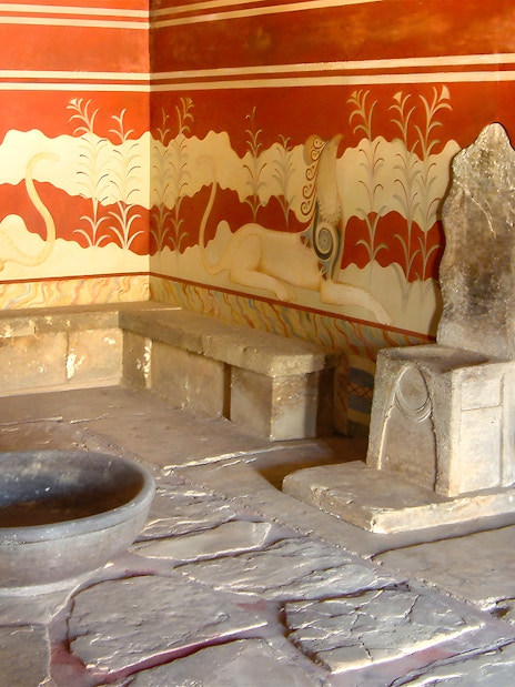 Throne room at Knossos Palace with stone seat and frescoes.