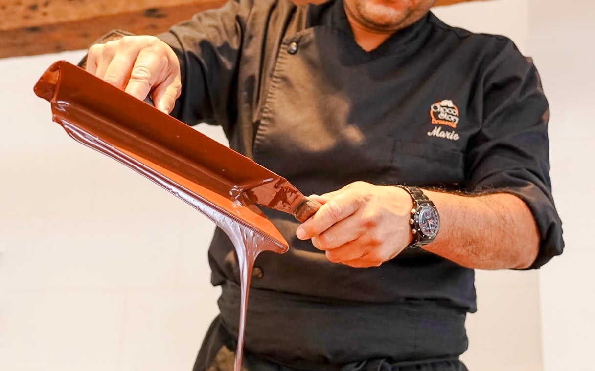 Host demonstrating chocolate pouring at Choco-Story Brussels Museum.
