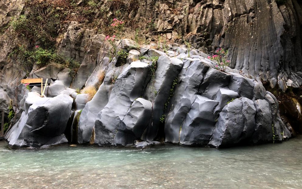 Alcantara Gorges basalt rock formations with clear water stream, Sicily.