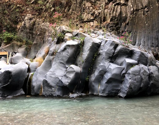 Quad bikes on rocky terrain at Alcantara Gorges, Sicily, with Mount Etna in the background.