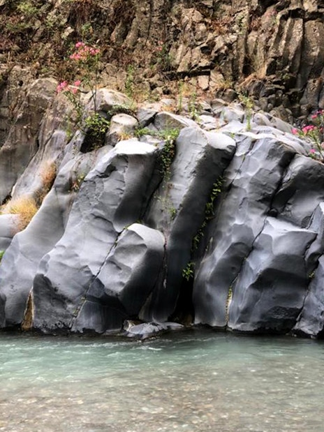 Alcantara Gorges basalt rock formations with clear water stream, Sicily.