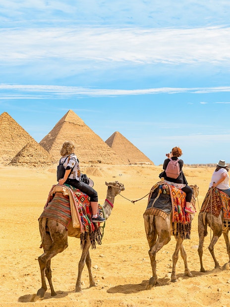 Tourists on camels approaching the Giza Pyramids in Egypt.