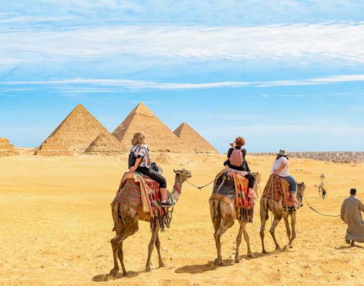 Tourists on camels approaching the Giza Pyramids in Egypt.