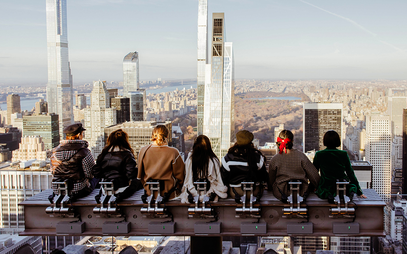 Visitors seated on a rooftop edge overlooking New York City skyline at Rockefeller Center.