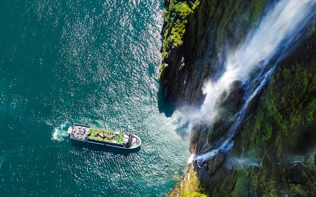 Cruise ship near waterfall in Milford Sound, New Zealand.