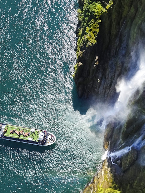 Cruise ship near waterfall in Milford Sound, New Zealand.
