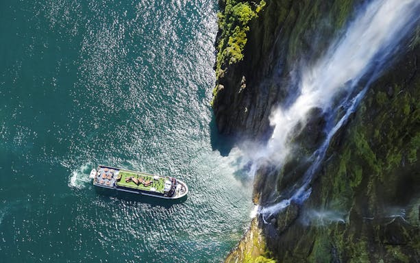 Cruise ship near waterfall in Milford Sound, New Zealand.