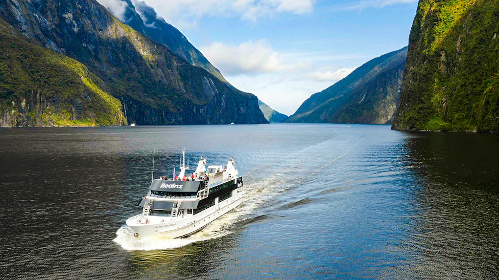 Milford Sovereign ship cruising through Milford Sound with scenic cliffs.