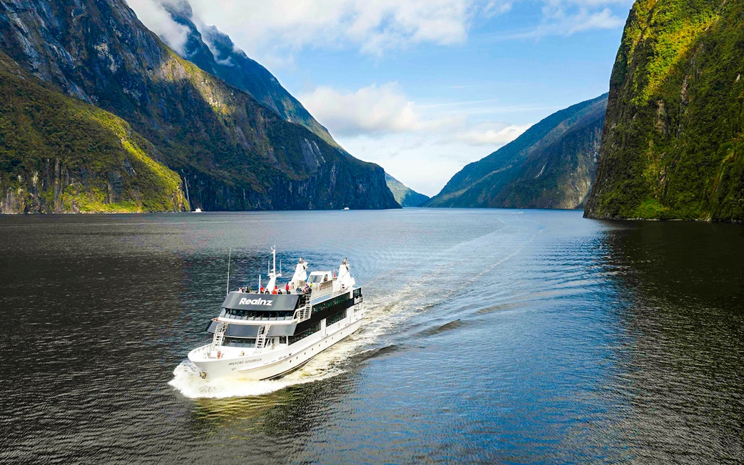 Milford Sovereign ship cruising through Milford Sound with scenic cliffs.