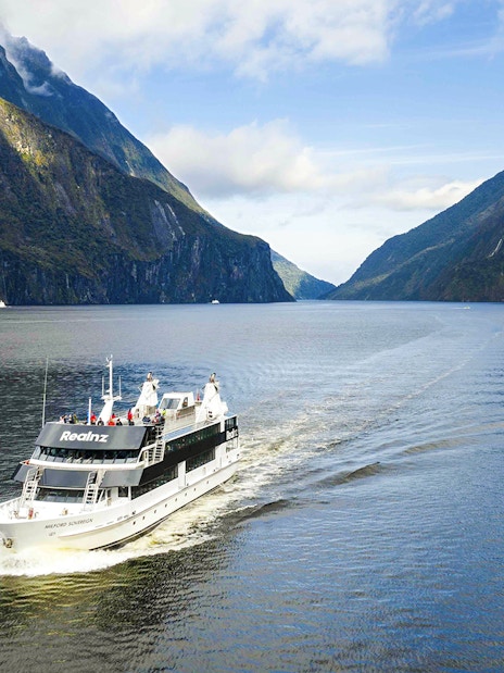 Milford Sovereign ship cruising through Milford Sound with scenic cliffs.
