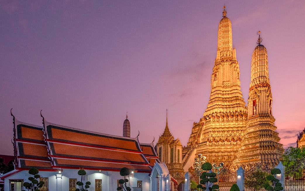 Wat Arun temple illuminated at sunset during Bangkok night tour.