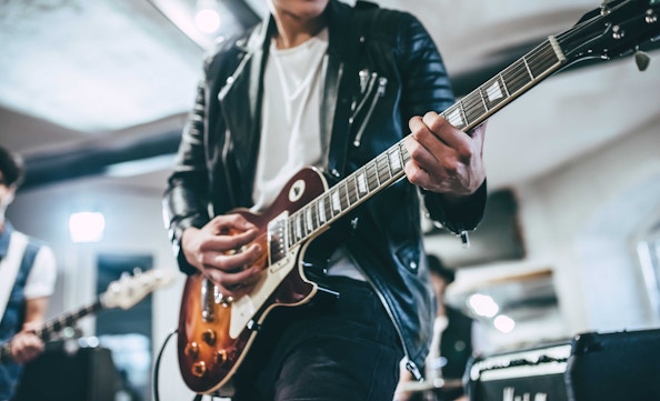 Guitarist playing electric guitar in a live music setting.