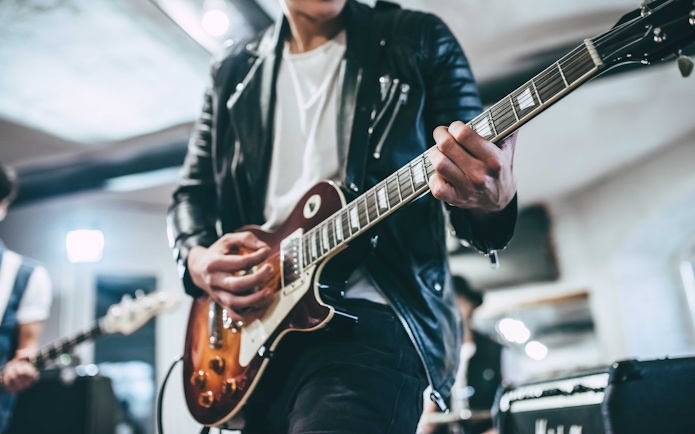Guitarist playing electric guitar in a live music setting.