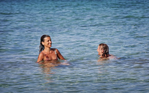People swimming in clear blue water near Ortigia Island during a sightseeing cruise.