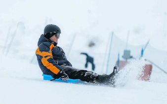 Tourist sledding on snow at Valle Nevado ski resort.