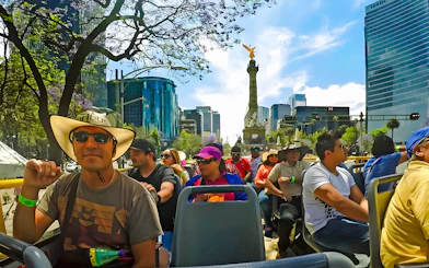 Tourists on an open-top bus near the Angel of Independence in Mexico City's historic center.