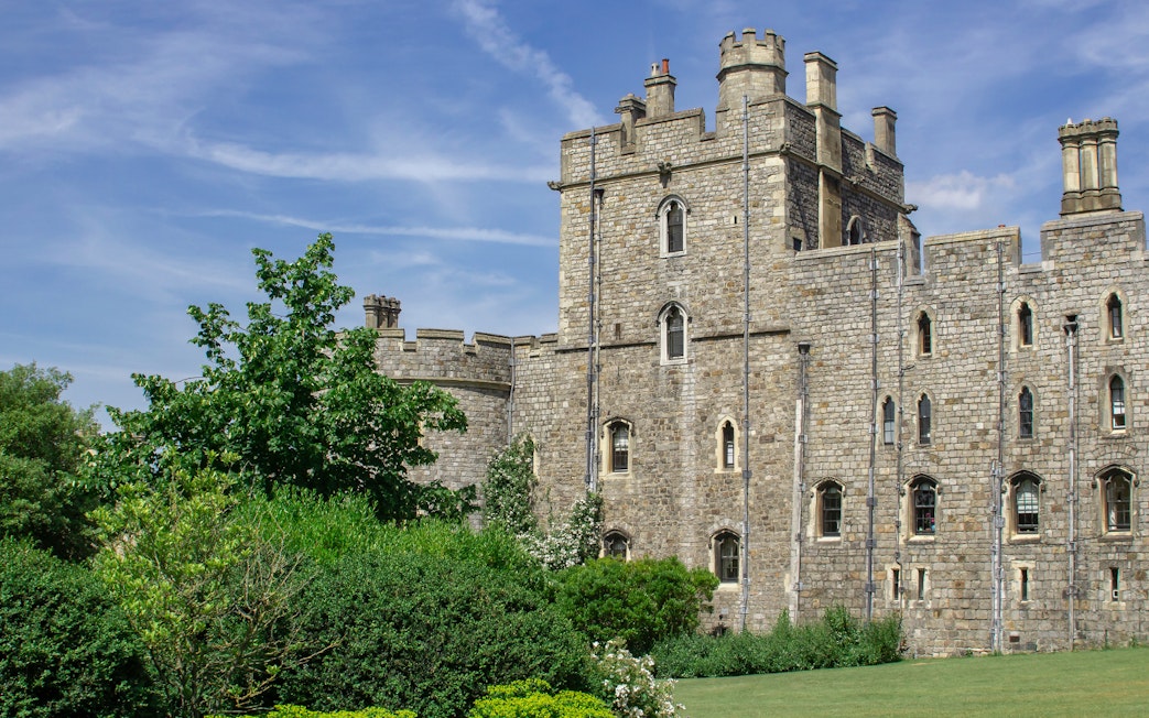 Windsor Castle stone exterior with lush greenery and blue sky.