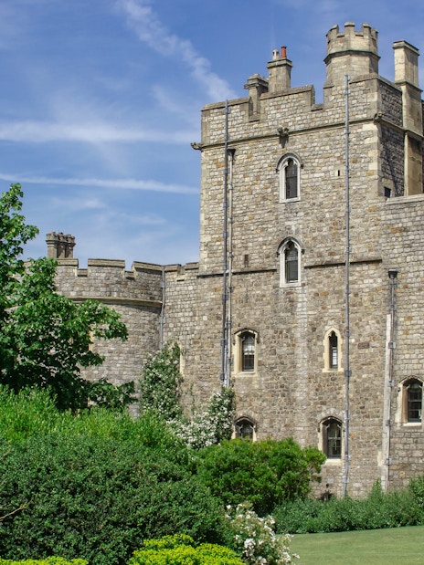 Windsor Castle stone exterior with lush greenery and blue sky.