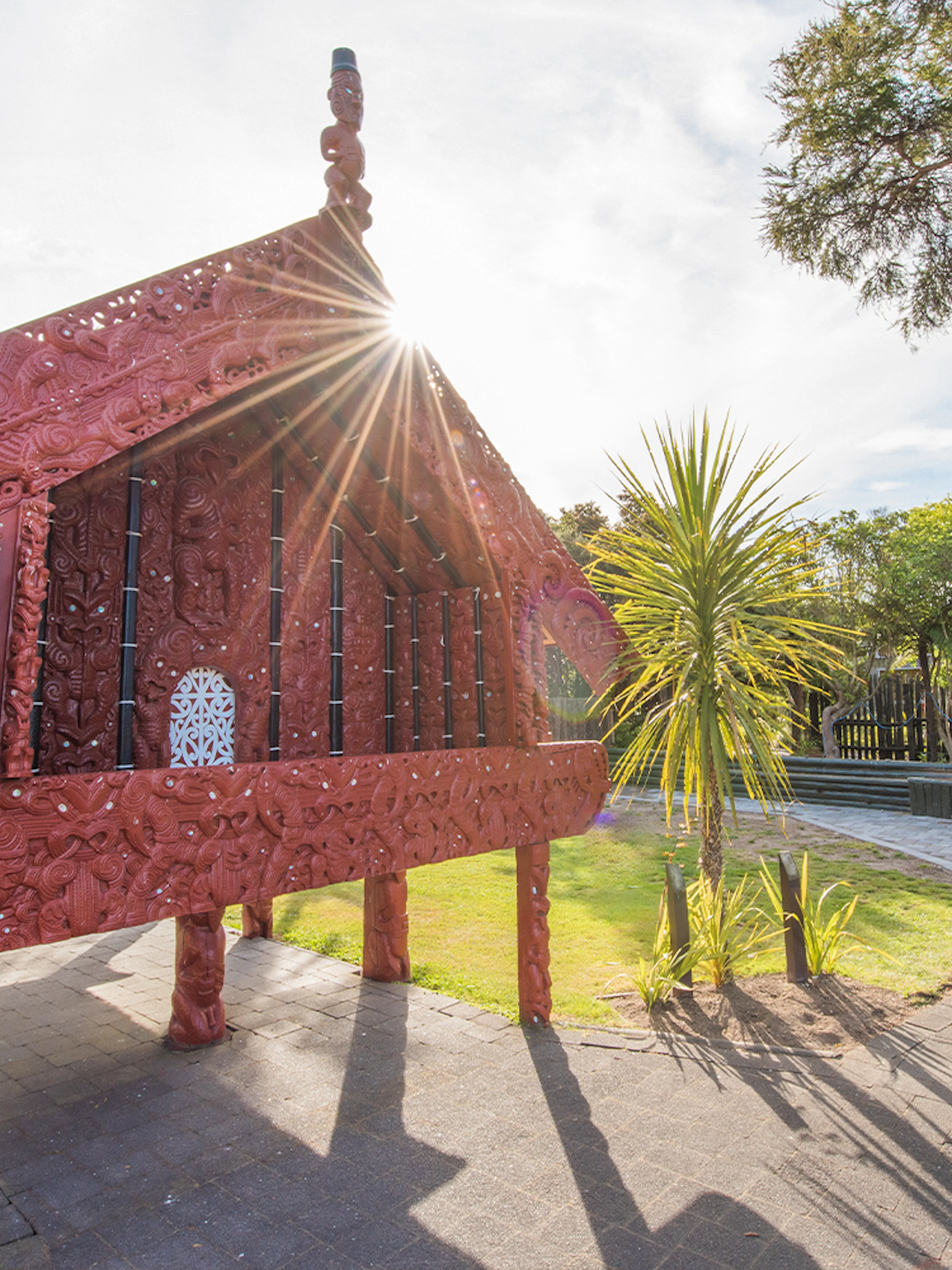 Traditional Māori carving at Te Puia, Rotorua, New Zealand, with sunlight streaming through.