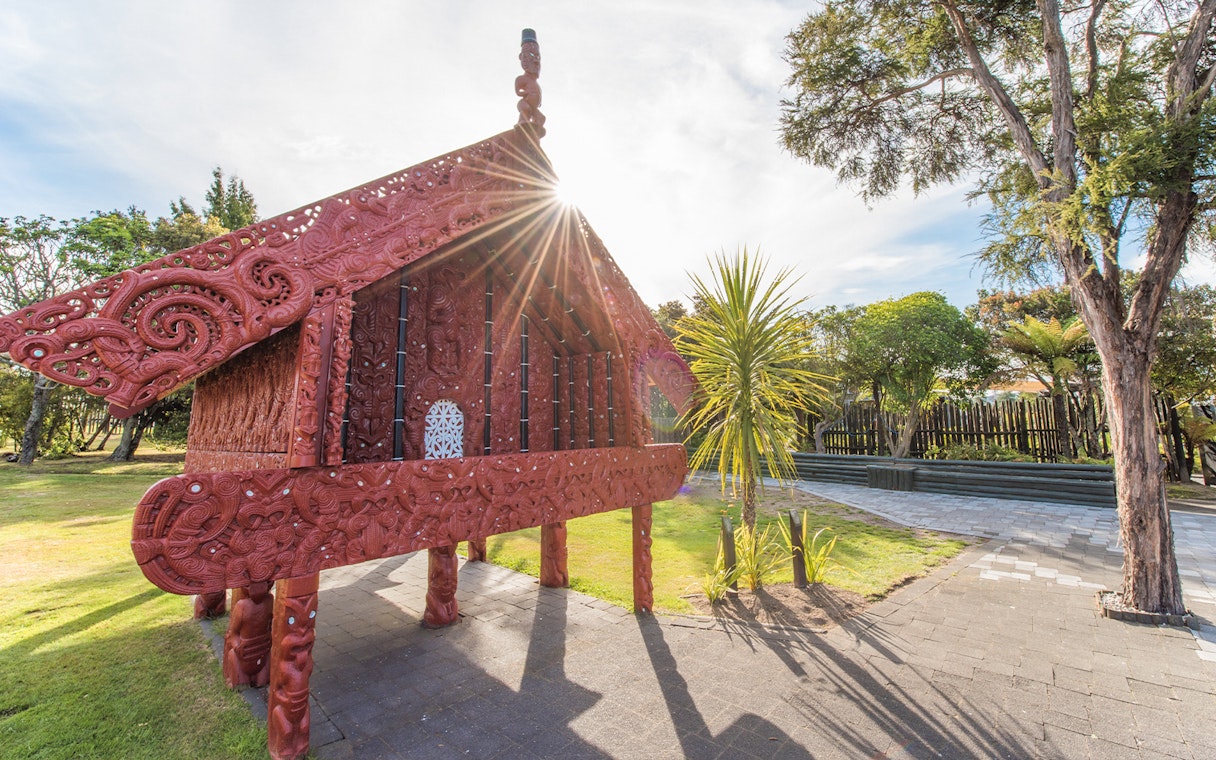 Traditional Māori carving at Te Puia, Rotorua, New Zealand, with sunlight streaming through.