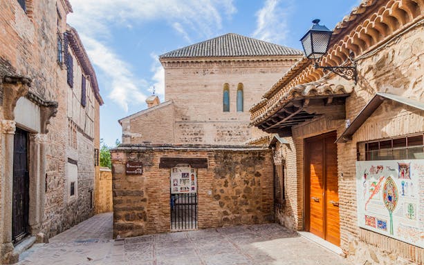 Historic alleyway in Toledo with stone buildings and signage for Museo del Greco.