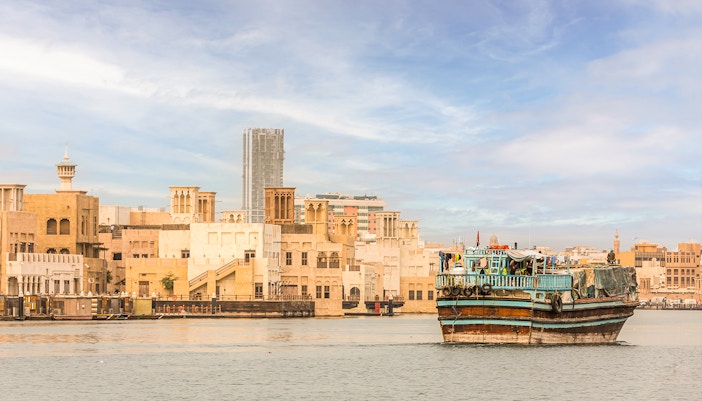 Dhow ship in front of the old city skyline.