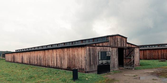 Wooden barrack at Stutthof Concentration Camp, Poland, under cloudy sky.