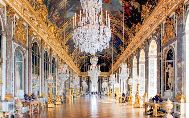 Hall of Mirrors in Versailles Palace with chandeliers and ornate decor.