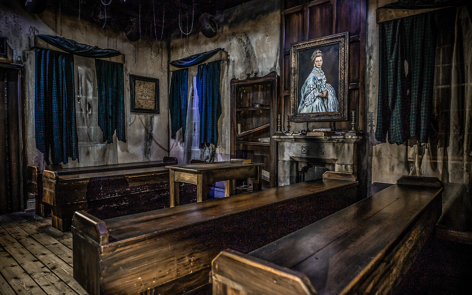 Edinburgh Dungeon room with wooden benches and a portrait, part of Castle Ghosts tour.