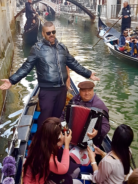 Gondola ride in Venice with musician playing accordion and singer performing.