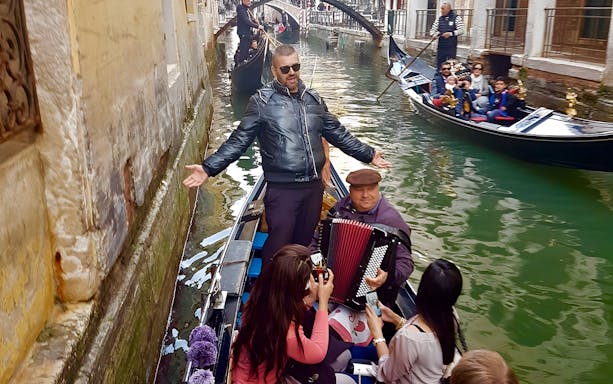 Gondola ride in Venice with musician playing accordion and singer performing.