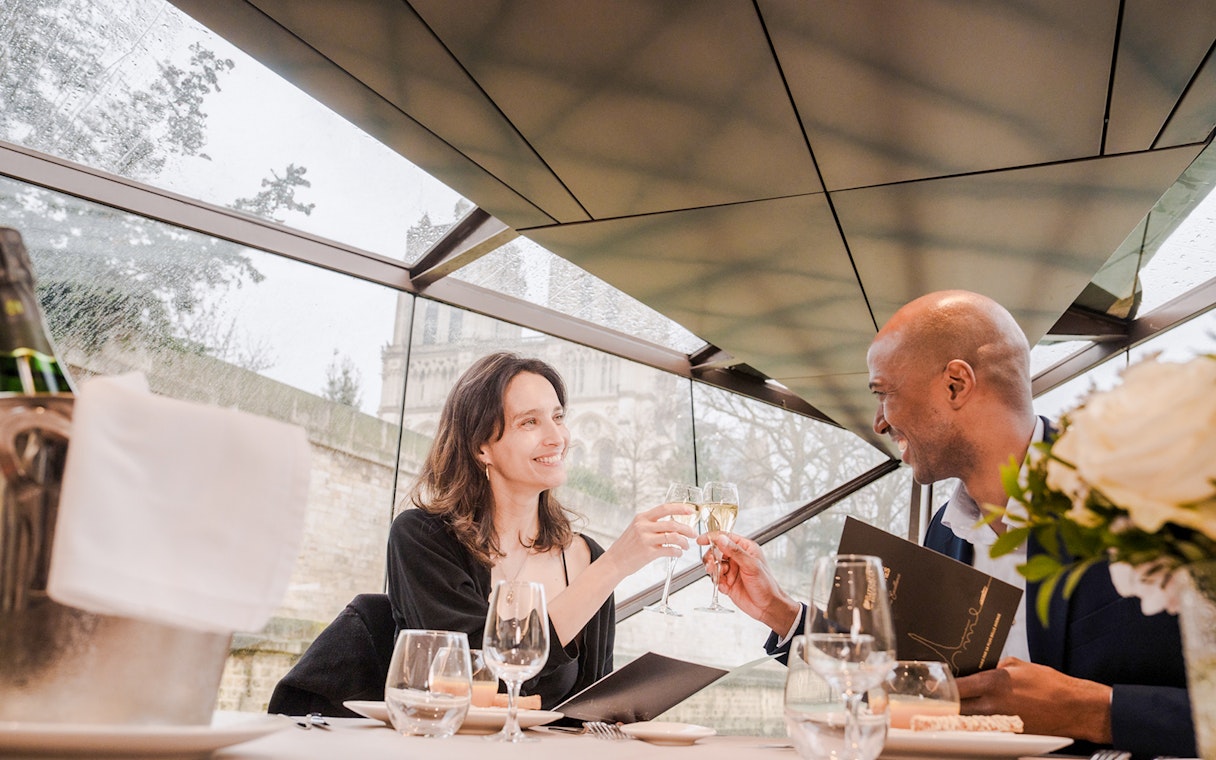 Couple toasting with champagne on a Seine River lunch cruise in Paris.